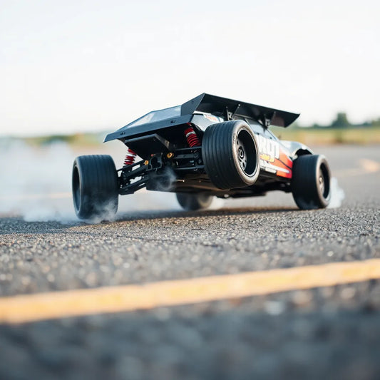 RC drift car mid-slide with visible wheel traction and light tire smoke on an asphalt track